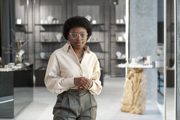 Young african clerk or owner of jewelry store standing against displays