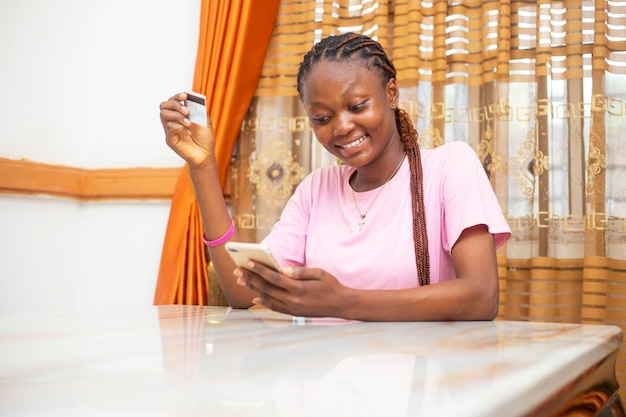 Young African Female Online Shopping with Card and Phone at Home