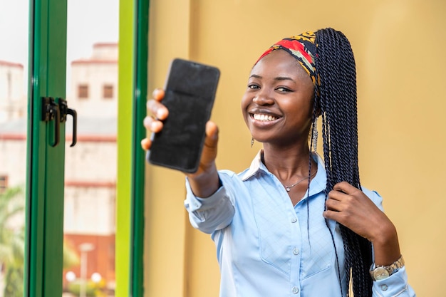 Молодая африканская девушка показывает экран телефона