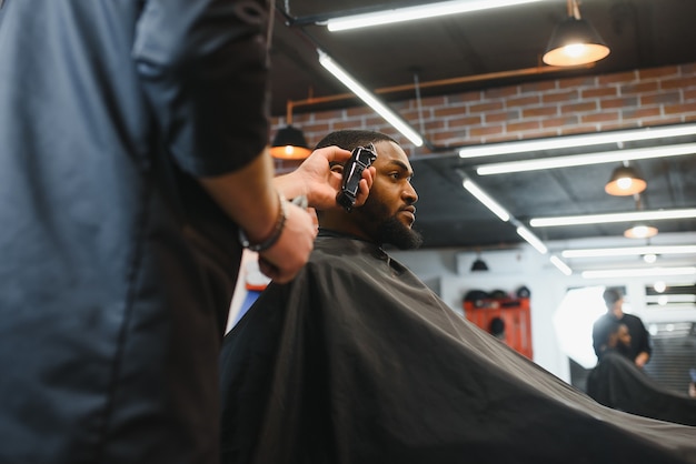 Молодой африканский парень делает новую стрижку в парикмахерской