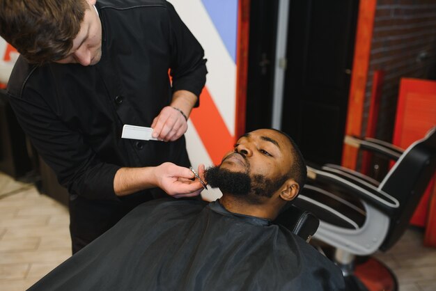 Young African guy getting new haircut in barber salon