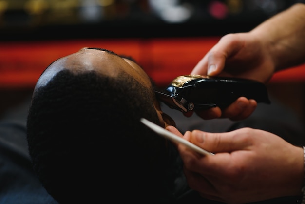 Young African guy getting new haircut in barber salon