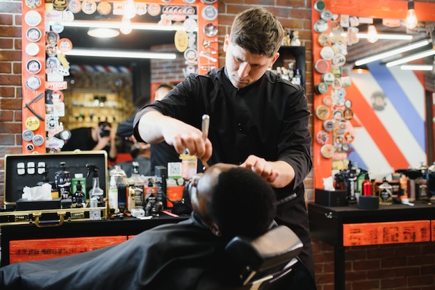 Young African guy getting new haircut in barber salon