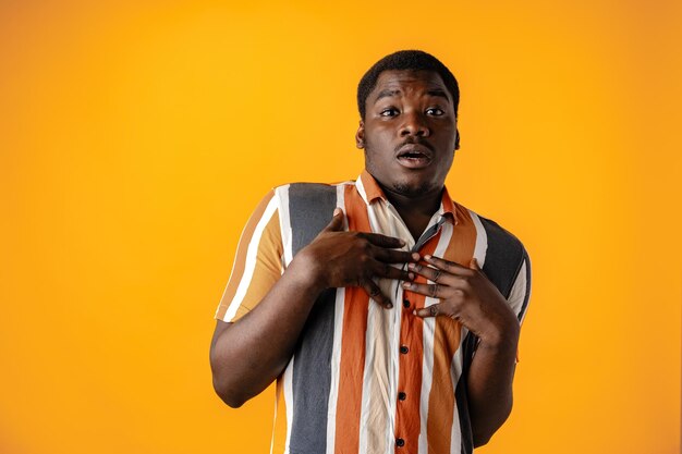 Young african man afraid of something against yellow background