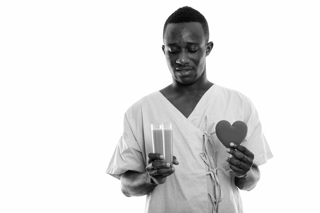  young African man as hospital patient isolated against white wall in black and white