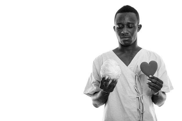  young African man as hospital patient isolated against white wall in black and white