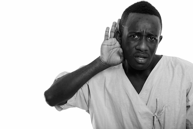 молодой африканец как пациент больницы изолирован у белой стены в черно-белом