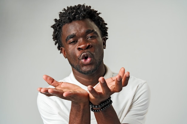 Young african man blowing a kiss against gray background