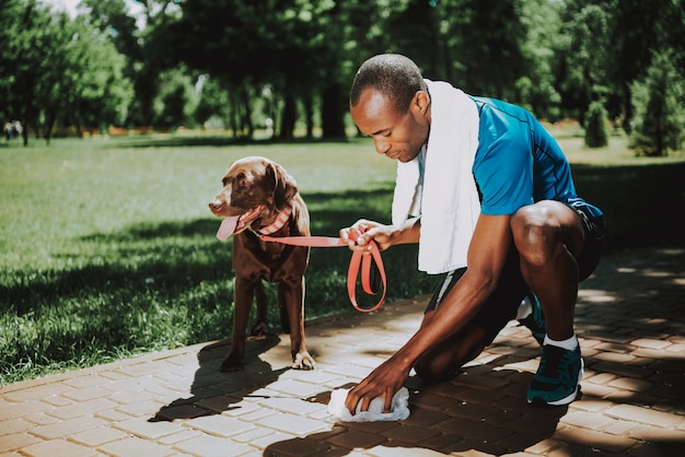 若いアフリカ人は犬の後をクリーンアップします。