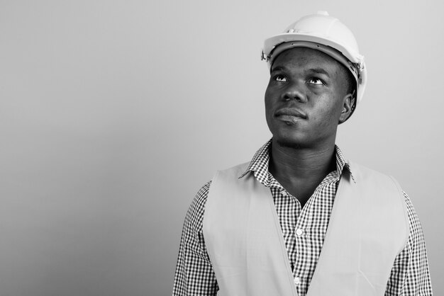 young African man construction worker against white wall. black and white