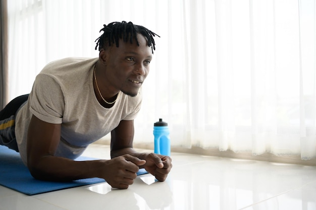 Young African man doing yoga exercise in the living room of his homewith the pleasure