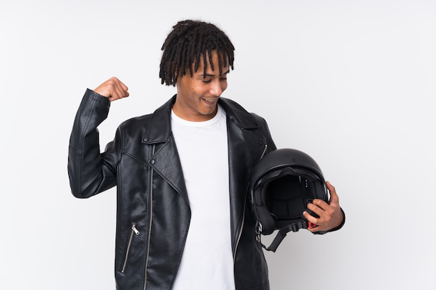 Young African man holding a motor helmet over wall