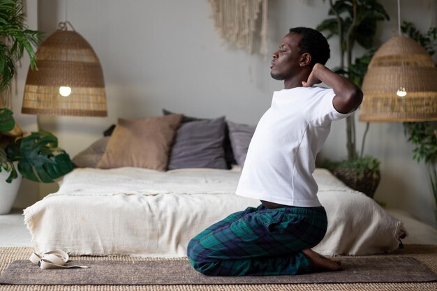 Young african man making asana exercises for shoulders stretching