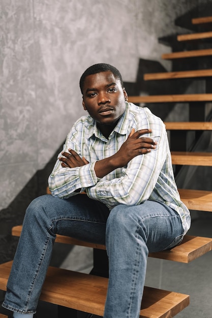 Young african man sitting on a wooden ladder in a room portrait