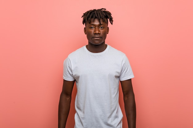 Young african man standing against pink wall