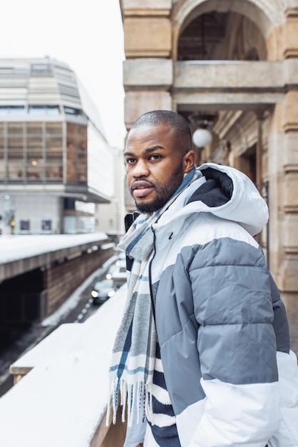 Young African man on street snow winter season city portrait