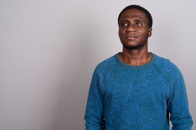 Young African man wearing blue long sleeved shirt on gray