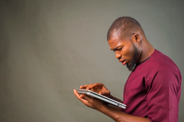 A young african man wearing brown cloth felt shocked, happy, thoughtful about he saw on his smartphone, telephone and phone