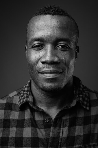 Photo young african man wearing checkered shirt against gray wall. black and white