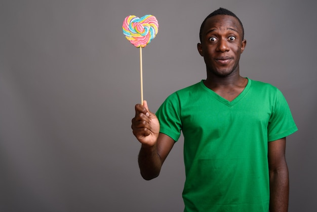 Young African man wearing green shirt on gray wall