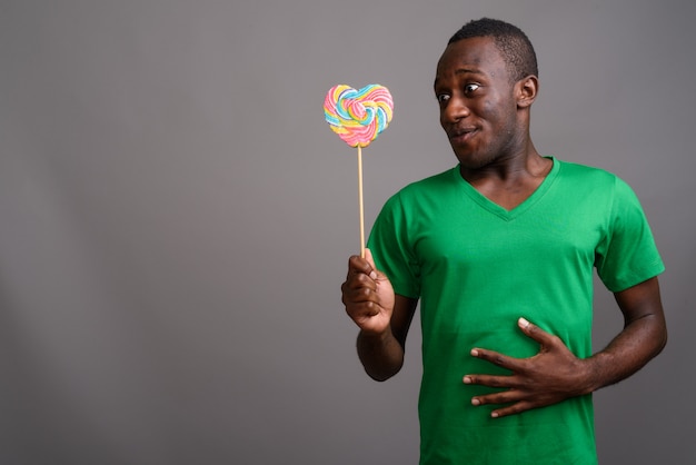 Young African man wearing green shirt on gray wall