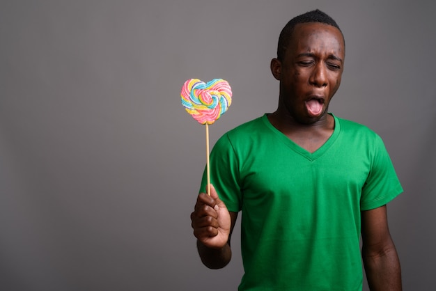 Young African man wearing green shirt on gray wall