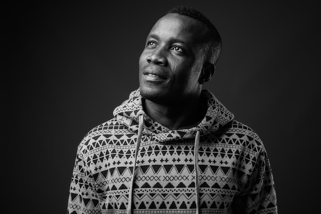 young African man wearing hoodie against gray wall. black and white