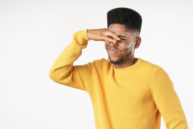 Young african man with bad smell expression over white background