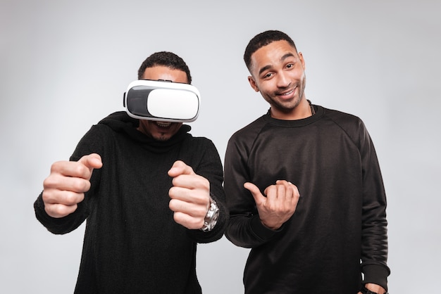 Young african men standing while using virtual reality device.