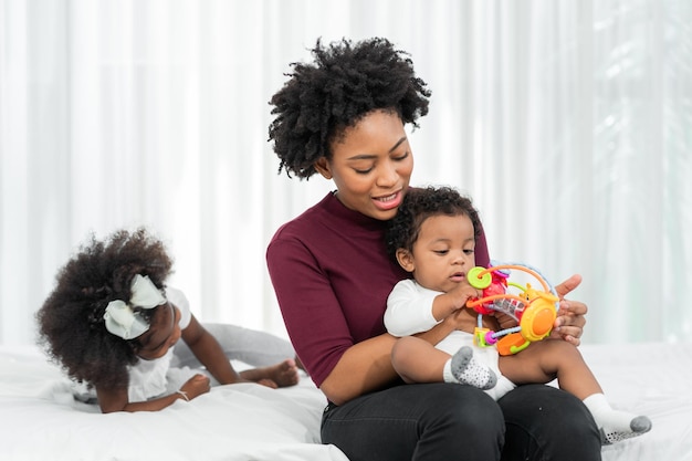 A young African mother raises her children and plays with them lovingly at home.