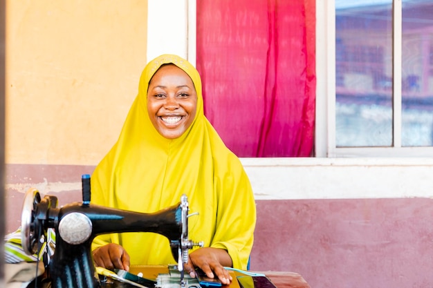 Young African muslim fashion designer using sewing machine in her workshop