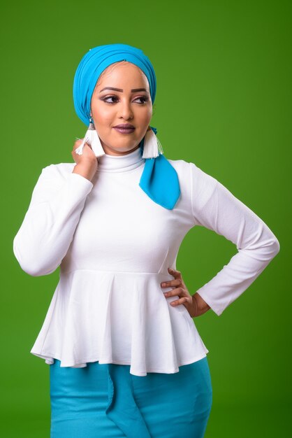 Young African Muslim woman against chroma key with green wall