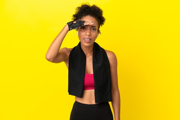 Photo young african sport woman isolated on yellow background looking far away with hand to look something