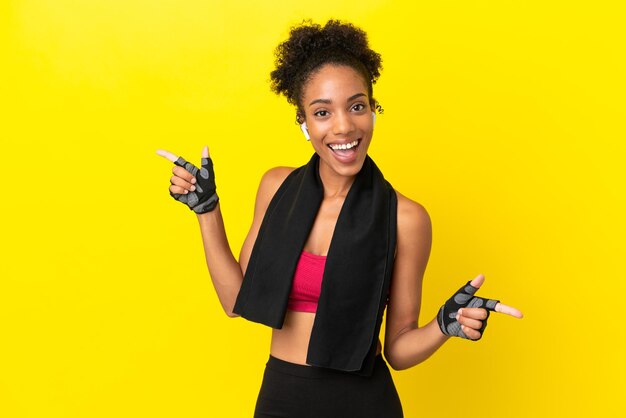 Young african sport woman isolated on yellow background pointing finger to the laterals and happy