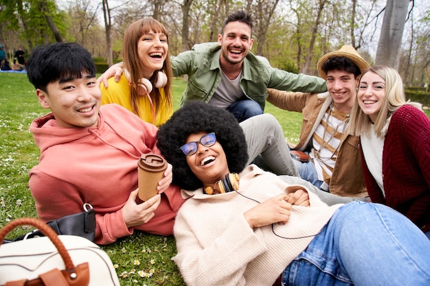 写真 肖像画のためにポーズをとる幸せな友達のグループと一緒に草の上に横たわっている若いアフリカの女性アフロの