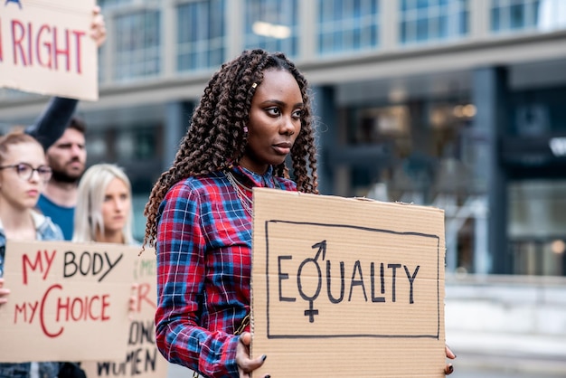 Young African woman leading a group of demonstrators in city streets multiracial people protesting for equality and empowerment feminism protest