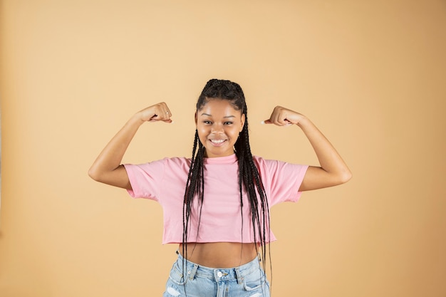 Photo young african woman pointing biceps strong woman sticking out arm