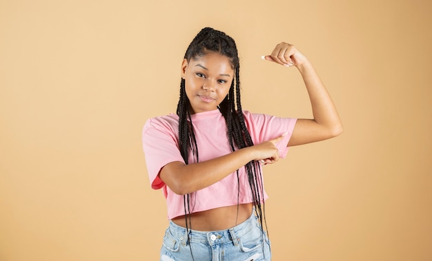 Young african woman pointing biceps strong woman