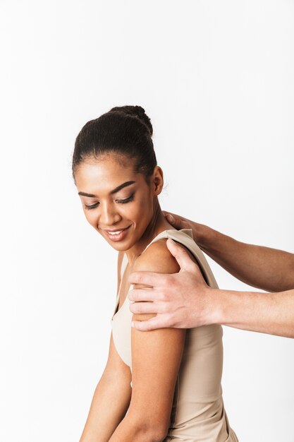 Foto giovane donna africana che si siede mentre la mano dell'uomo che tiene le sue spalle isolate su bianco