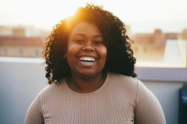 Foto giovane donna africana sorridente sulla fotocamera con il tramonto sullo sfondo focus sul viso