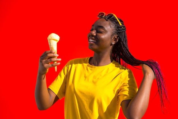 Молодая африканская женщина улыбается, ест мороженое.