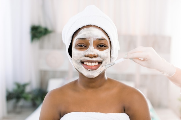 Photo young african woman in studio doing body care with refreshing facial mask for young and beautiful skin and relaxation