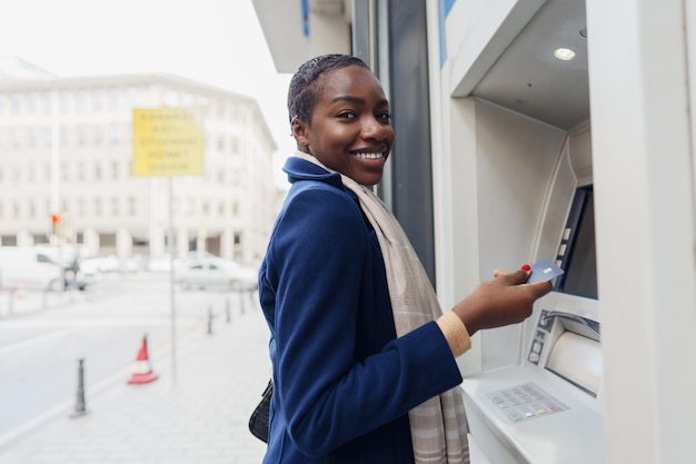 Young african woman withdrawing cash at the atm