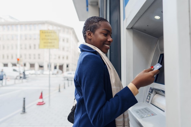 Young african woman withdrawing cash at the atm