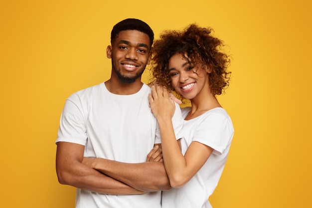 Young africanamerican couple posing on orange background