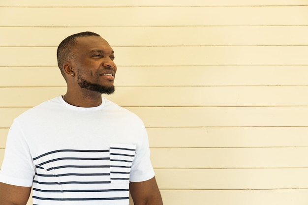 A young AfricanAmerican man poses for the camera against a wall background