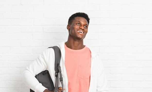 Young afro american man student posing with arms at hip and laughing