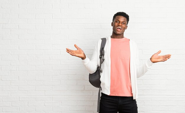 Young afro american man student with surprise and shocked facial expression