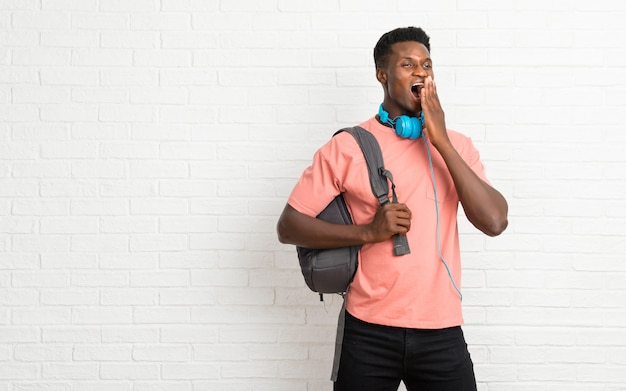 Young afro american man student yawning and covering wide open mouth with hand. Sleepy expression