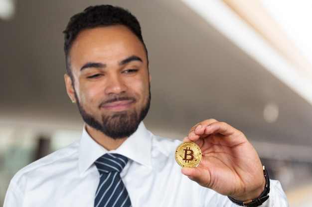 Foto giovane uomo afroamericano con bitcoin in mano